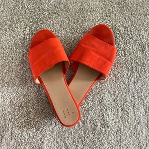 Red/orange faux suede slip on flat sandals.
